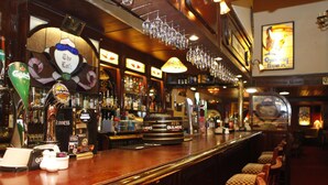 Un bar con numerosi rubinetti per la spina, tra cui Guinness e Bulmers, bicchieri appesi sopra il bancone e un ripiano ben fornito di diverse bottiglie.