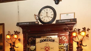 Un camino con un cartello Jameson, un orologio e insegne Guinness sopra.