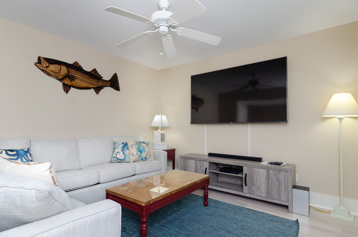 A living room with a sofa, coffee table, TV, and a ceiling fan.