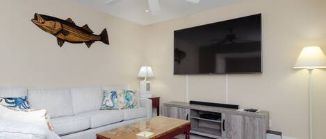 A living room with a sofa, coffee table, TV, and a ceiling fan.