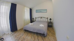Ein Schlafzimmer mit einem Bett, einem Nachttisch, einer Lampe und einem Bild an der Wand.