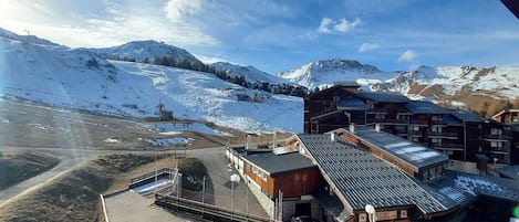 A building with a sloped roof, a parking area, and a view of snow-covered mountains.