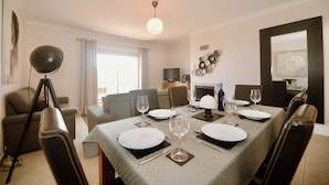 Un comedor con una mesa dispuesta para cuatro personas, un sofá y un trípode en primer plano.