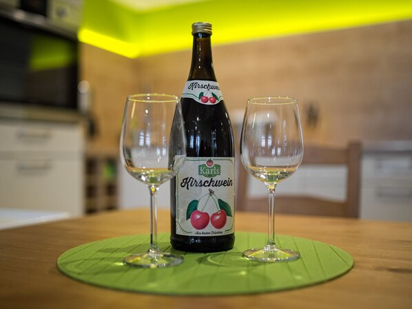 A bottle of Kirschwein with two glasses on a table.