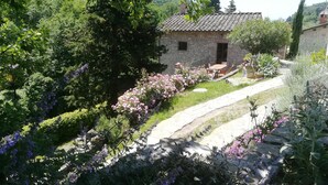 Une maison en pierre avec un jardin, un chemin pavé et un petit espace patio.