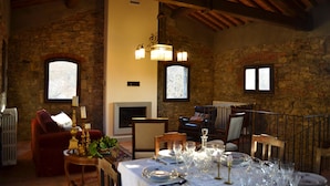 Un coin repas avec une table dressée pour le repas, des murs en pierre et une cheminée.