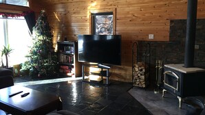 Ett mysigt vardagsrum med träinredning, en öppen spis, en tv och en julgran.