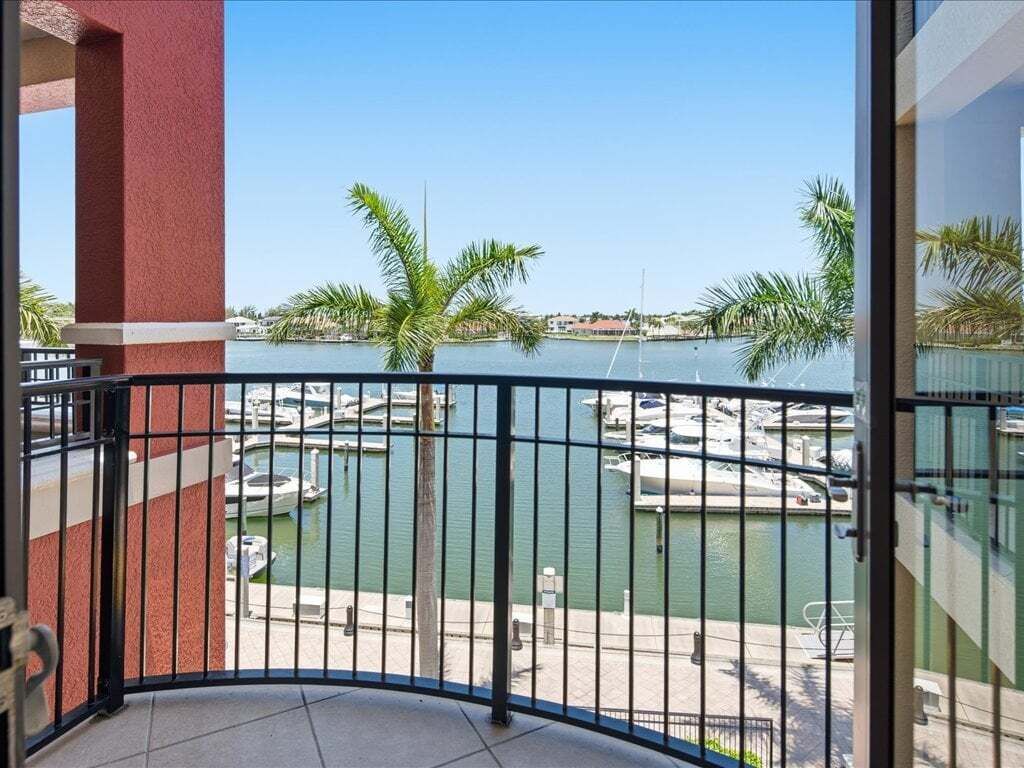 A balcony with a view of a marina, palm trees, and a clear sky.