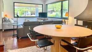 Una sala de estar moderna con un ventanal grande, una mesa de comedor redonda y una parrilla empotrada.