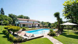 Una casa con piscina, rodeada de un jardín cuidado y un cielo despejado.