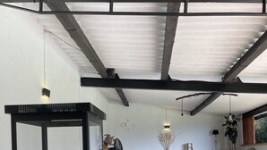 Una sala de estar moderna con chimenea de vidrio, sofá gris, mesa de centro de madera y un comedor con sillas blancas.