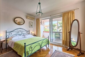 A bedroom with a bed, a standing mirror, a window with curtains, and a view of the outside. - Villa Little Castle with private pool (Kukci)