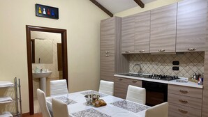 A dining area with a table set for four, a kitchen with wooden cabinets, and a tiled backsplash.