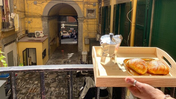 A narrow alleyway with a wooden tray of pastries and a glass of water.