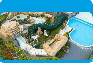 A pool area with a water slide, a hot tub, and a separate swimming pool.