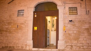 Un edificio de piedra con puerta de madera, una ventana pequeña y un letrero que indica que es una Muraglie dell Castello.