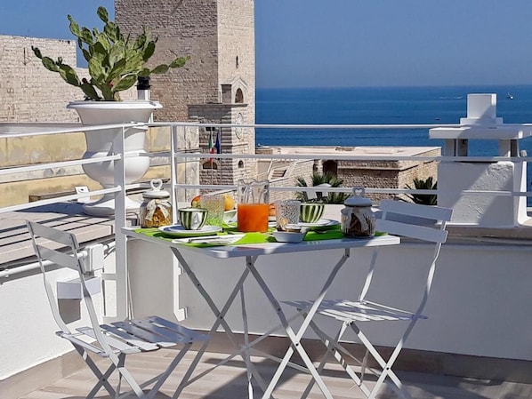 A rooftop terrace with a table set for breakfast, overlooking the sea. - Muragie del Castello (Trani)