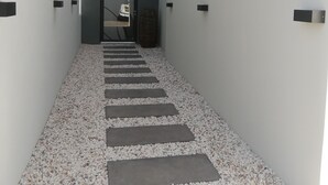A narrow, modern corridor with a gravel path and a door at the end.