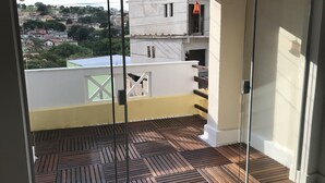 Ein Balkon mit einem gemusterten Boden, einer weißen Wand und Blick auf eine Wohngegend.