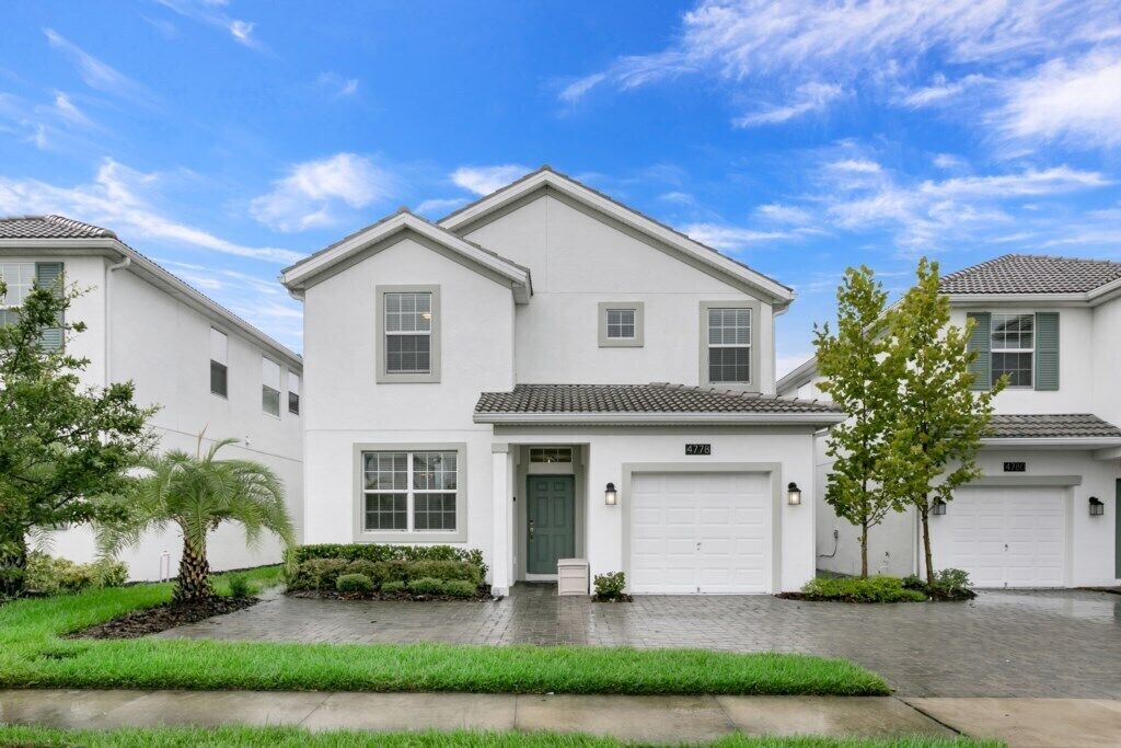 A modern two-story house with a white exterior, a front garage, and a well-maintained lawn.