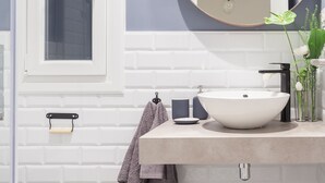 Une salle de bain avec un lavabo blanc, un miroir rond et une fenêtre.