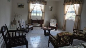 A room with a ceiling fan, two windows with curtains, a desk, and several chairs. - Beachfront-Chandler'sCoast-10mins to Holetown-2 BR apartment-private gated villa (Weston)