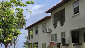 A two-story building with a white facade, multiple windows, and an air conditioning unit. - Beachfront-Chandler'sCoast-10mins to Holetown-2 BR apartment-private gated villa (Weston)