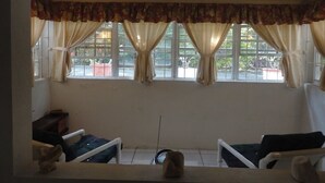 A room with a large window, two chairs, a small table, and a decorative item on the windowsill. - Beachfront-Chandler'sCoast-10mins to Holetown-2 BR apartment-private gated villa (Weston)