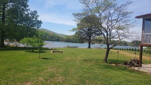 Eine Wiese mit einem See, Bäumen und einer hölzernen Konstruktion.