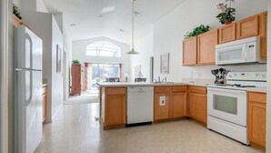 Een moderne keuken met houten kastjes, een witte vaatwasser, een magnetron en een oven.