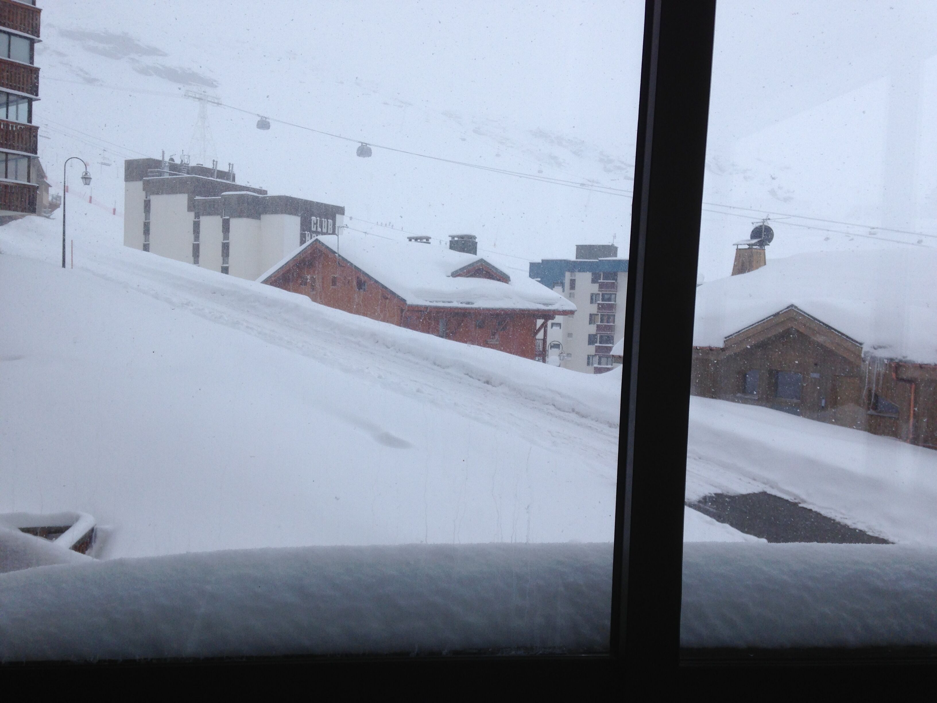 A snowy landscape with buildings and a ski lift in the background.