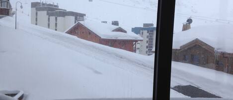 A snowy landscape with buildings and a ski lift in the background.