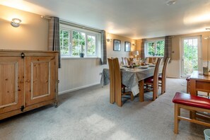 Un coin repas avec une table en bois dressée pour quatre personnes, entourée de chaises hautes, d’un banc rouge et d’un meuble muni d’une poignée.