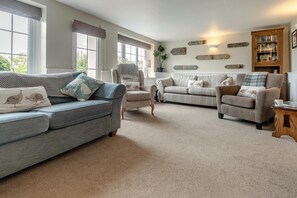 A living room with two sofas, a chair, a bookshelf, and decorative wall signs. - 3 Bed in Lynton (oc-keepba) (Ilkerton)