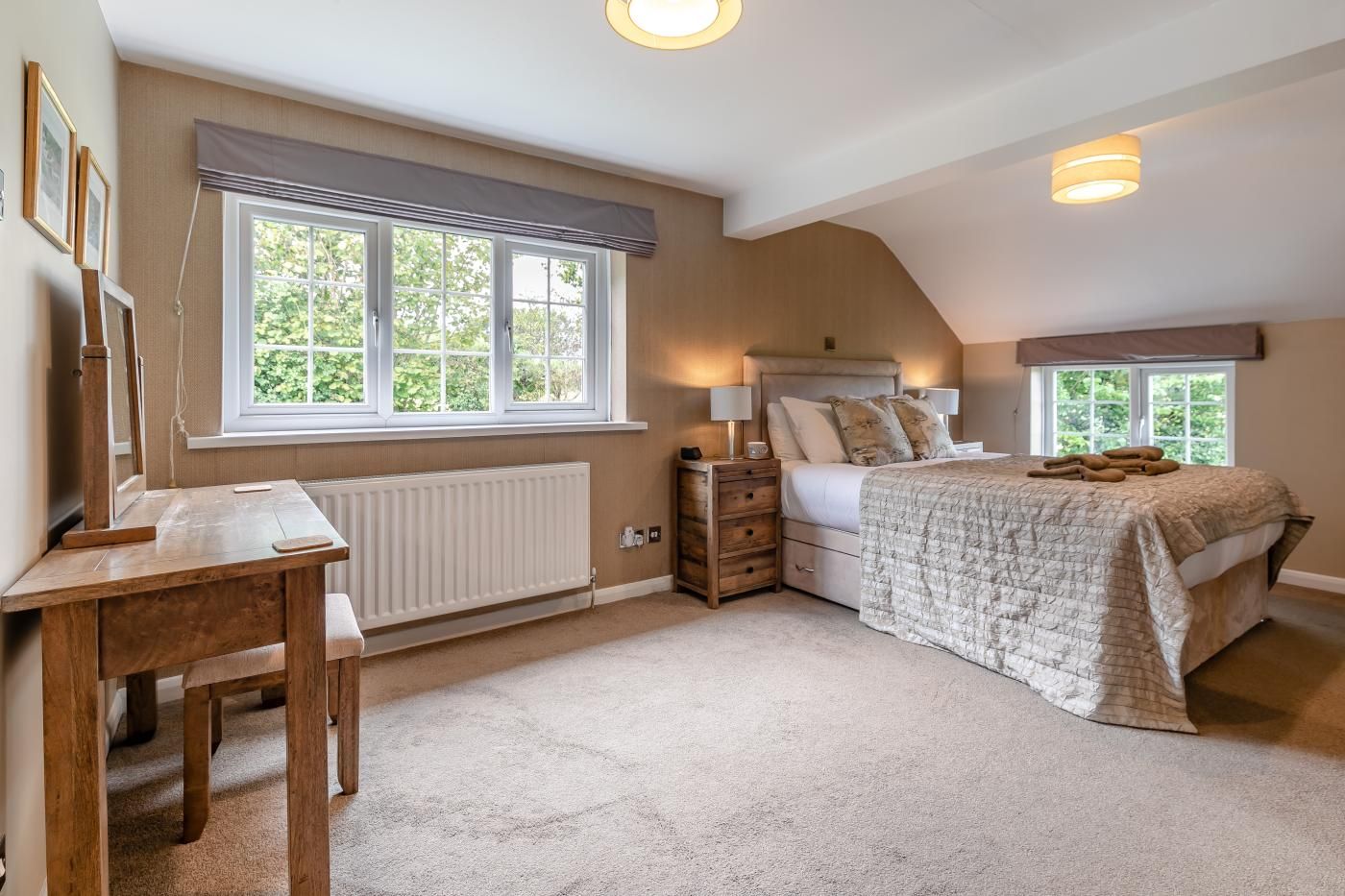 A bedroom with a bed, bedside tables, a desk, and a window.