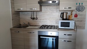 A modern kitchen with stainless steel appliances, wooden cabinets, and a built-in oven. - "Sa Dommu 'e su coro" apartment for 2. (Triei)