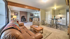 A living room with a leather sofa, a coffee table, a fireplace, and a kitchen area with bar stools. - Walkout Apartment w/ Mtn View on Cortez Ranch (Cortez)