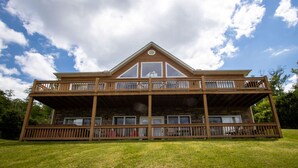 Une cabane en bois à deux étages, dotée d’un balcon à l’étage supérieur, et entourée d’une pelouse verdoyante.