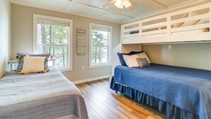 Une chambre avec deux lits, un ventilateur de plafond et de grandes fenêtres.
