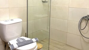 Moderni kylpyhuone, jossa on wc, bidee ja lasinen suihkuseinä.