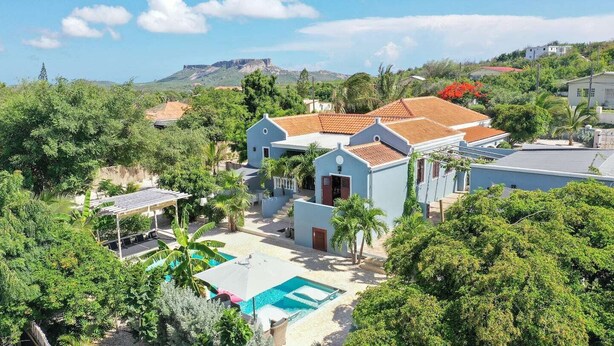 Um imóvel residencial com piscina, varanda coberta e vista para uma montanha.