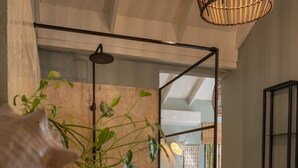 Um interior moderno com divisória de vidro, planta pendente, banco de madeira e luminária de teto singular.
