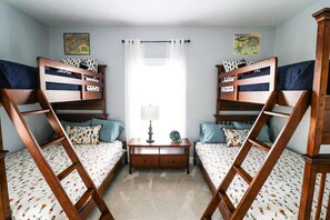 Ein Zimmer mit zwei Etagenbetten, einem Nachttisch mit Lampe und einem kleinen Tisch.