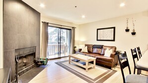 A modern living room with a fireplace, a sofa, a coffee table, and a dining area with chairs. - Spacious and Beautiful, Walk to ski, Wi-fi, Parking (Park City)