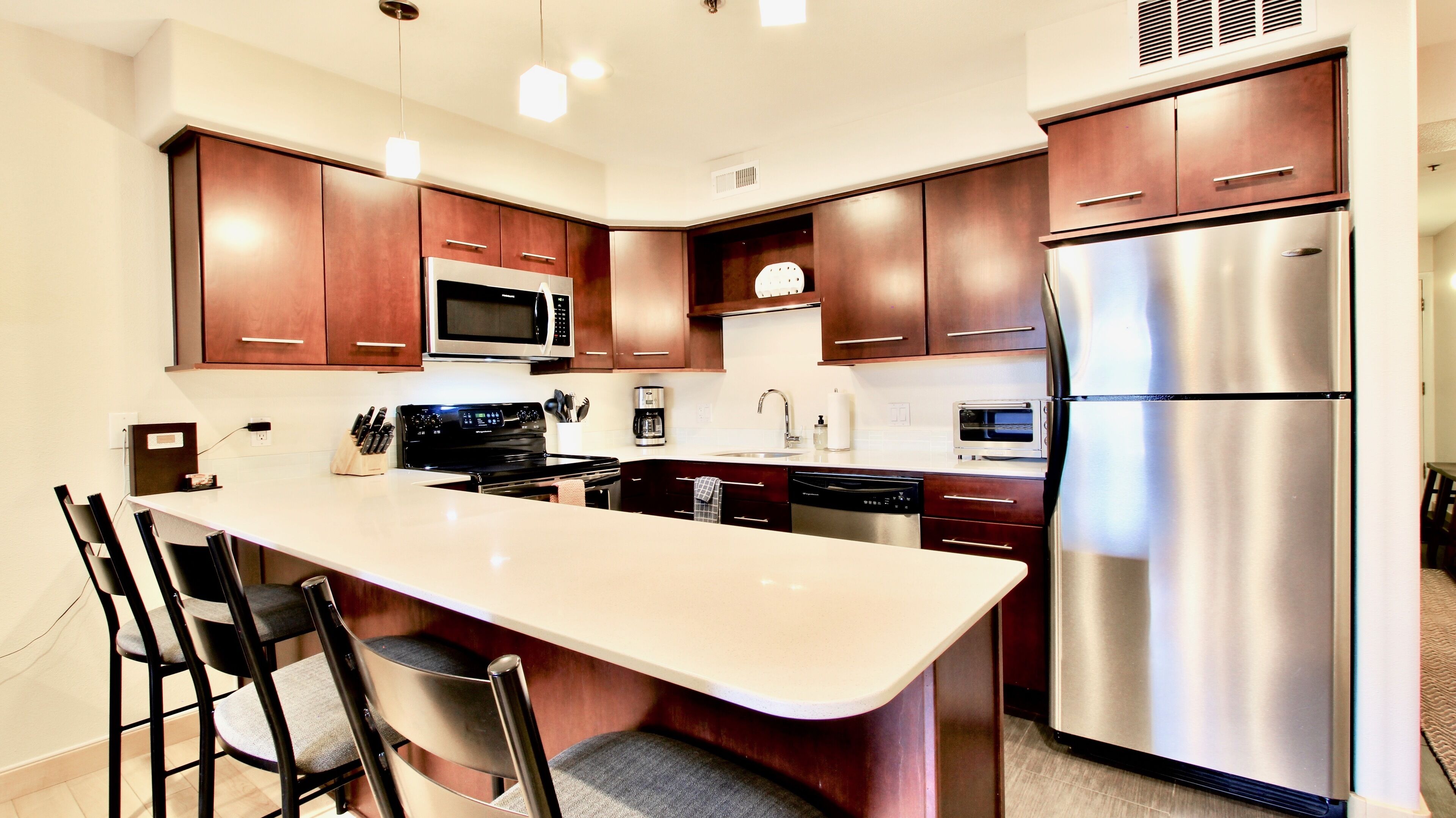 A modern kitchen with dark wood cabinets, stainless steel appliances, and a central island with bar stools.