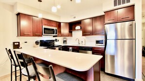 A modern kitchen with dark wood cabinets, stainless steel appliances, and a central island with bar stools. - Spacious and Beautiful, Walk to ski, Wi-fi, Parking (Park City)