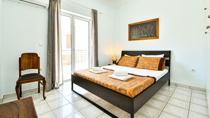 A bedroom with a bed, a chair, a painting, and a window with curtains. - Alcyone, Comfortable Home Close To Athens Airport (Artemis)