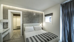 A modern hotel room with a large bed, a bedside table with a lamp, a wardrobe, and a view of the outside through a window. - Rocca Palazzaccio (Impruneta)