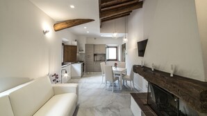 A modern living room with a fireplace, a dining area, and a kitchen. - Rocca Palazzaccio (Impruneta)