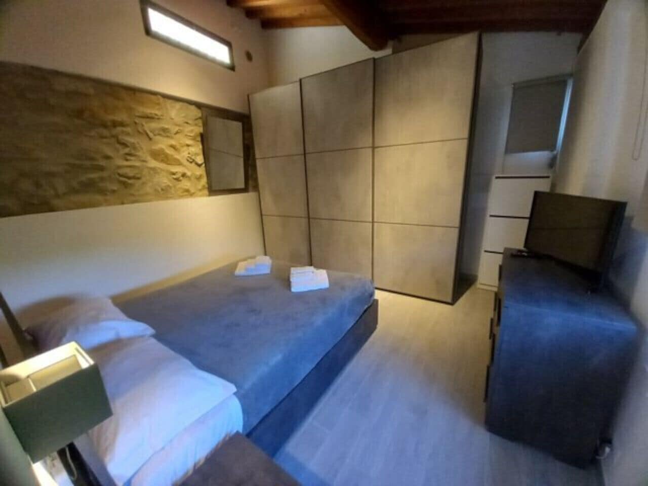A bedroom with a bed, a nightstand, a dresser, and a large mirror.